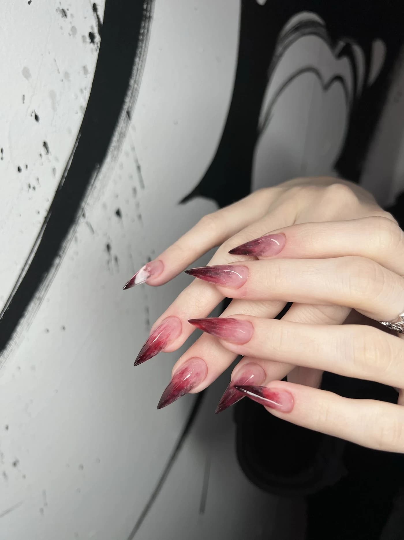 Long stiletto nails with a red ombré against the mural — Martyna's work